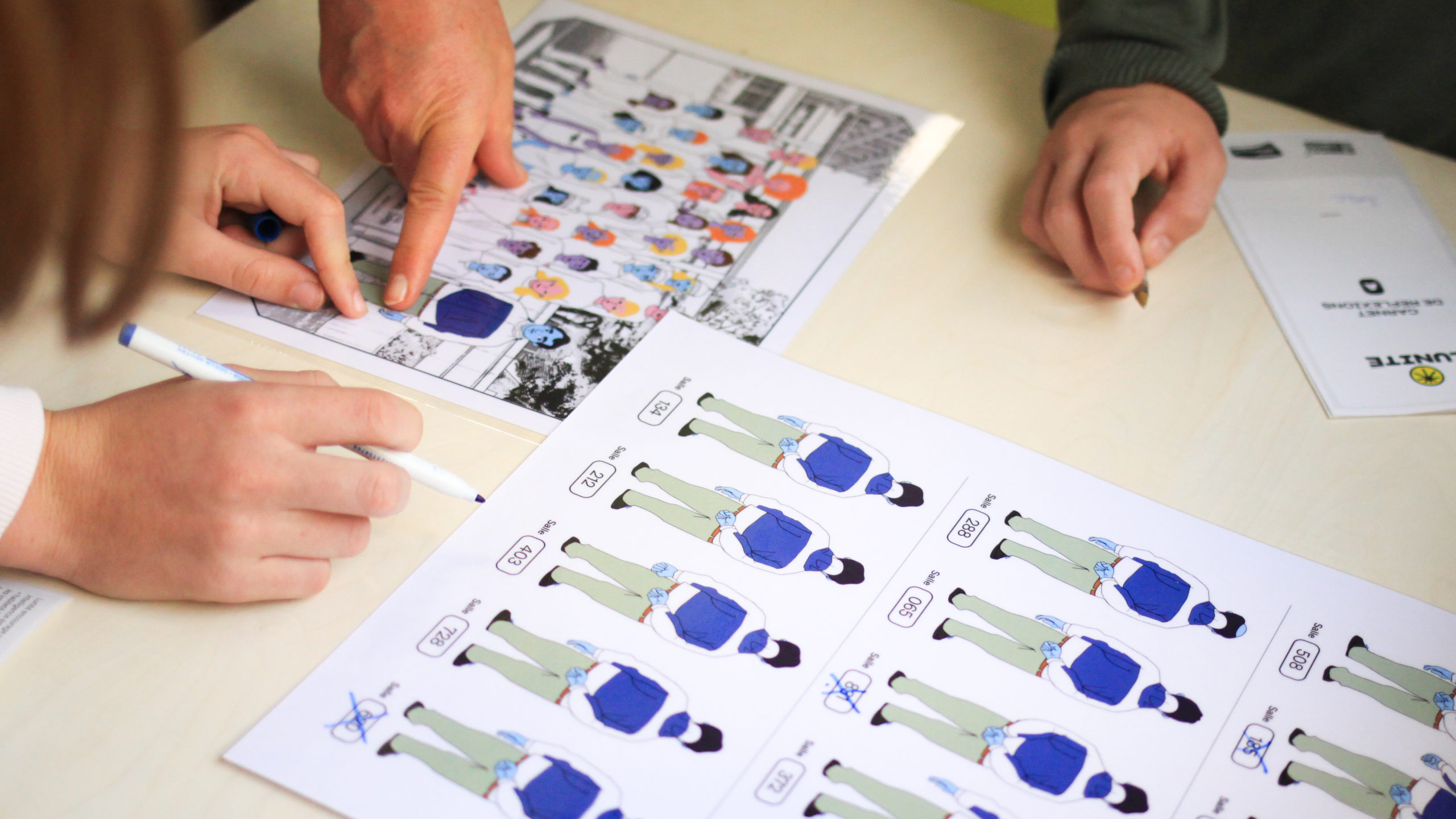 Photographie en gros plan sur des documents visuels disposés sur une table. L'ensemble des documents composent une énigme que plusieurs participants autour de la table tentent de résoudre.