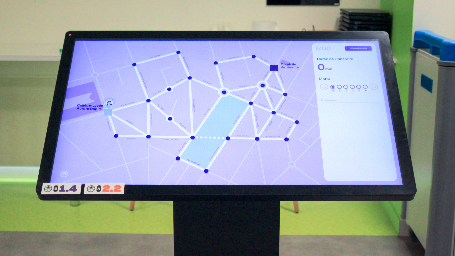 Photographie d'une grande table tactile. Sur l'écran figure une énigme sous la forme d'un plan de quartier, où un personnage doit être guidé de son collège à son domicile.