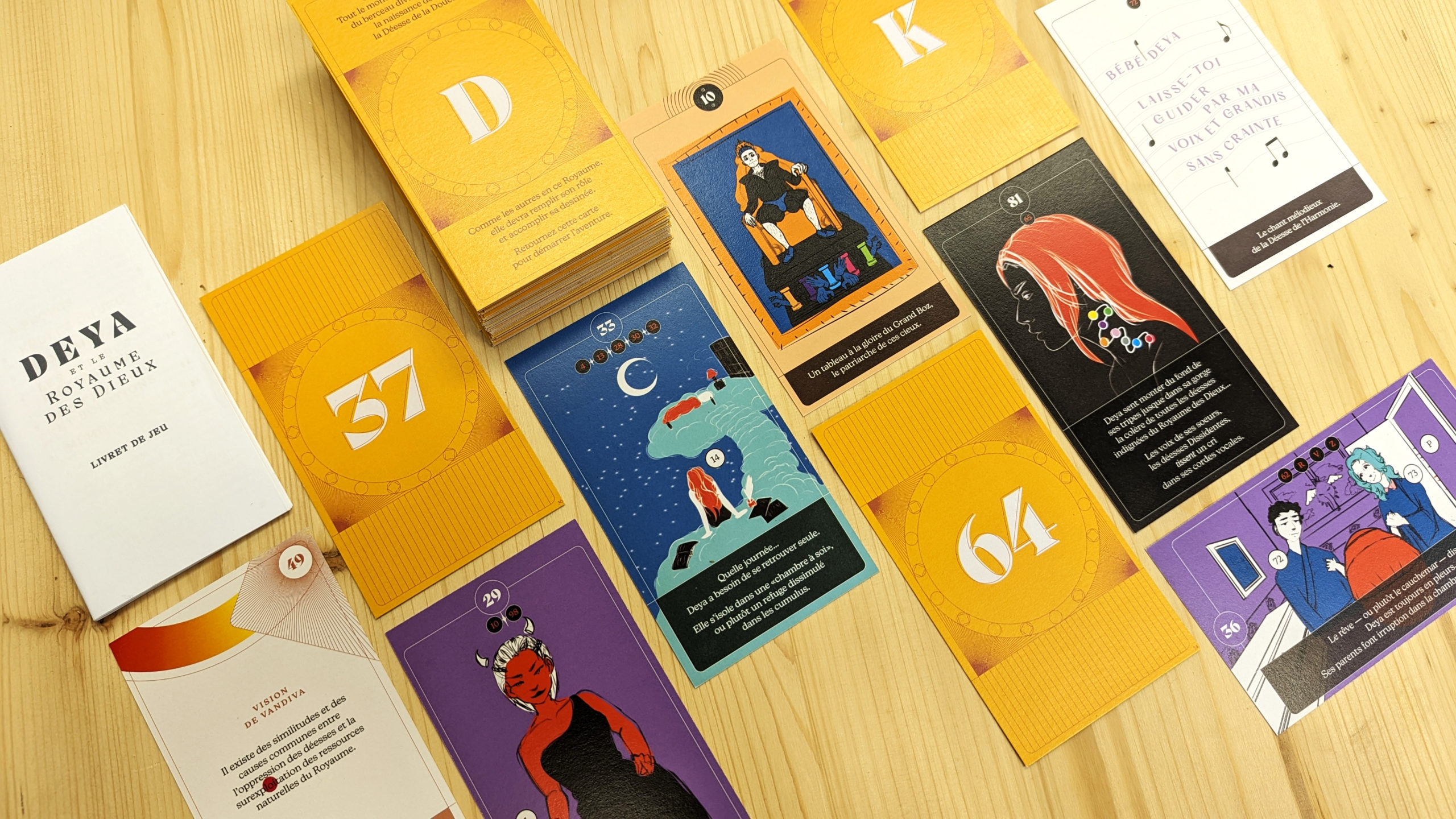 Photographie du prototype actuel du jeu. Une sélection de cartes illustrées sont présentées, de face et de dos.