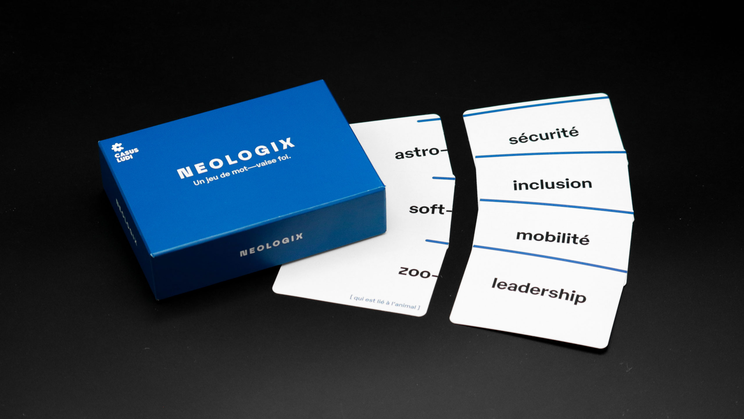 Photographie de présentation du jeu. La boite Néologix est présentée avec plusieurs cartes "Préfixe" (astro, soft, zoo) et "Terme" (sécurité, inclusion, mobilité, leadership).